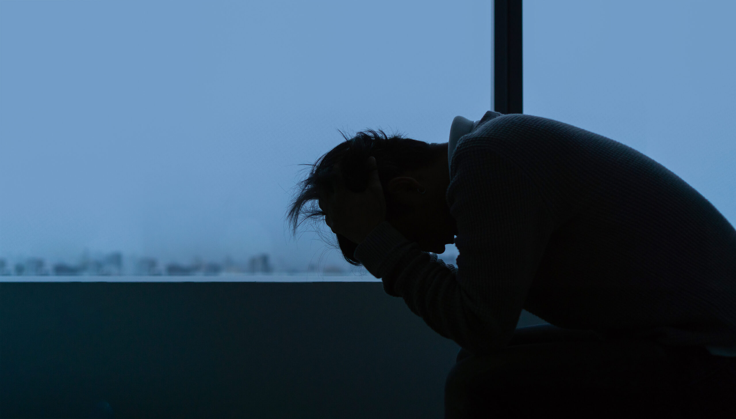 Young man sitting alone near window in evening time